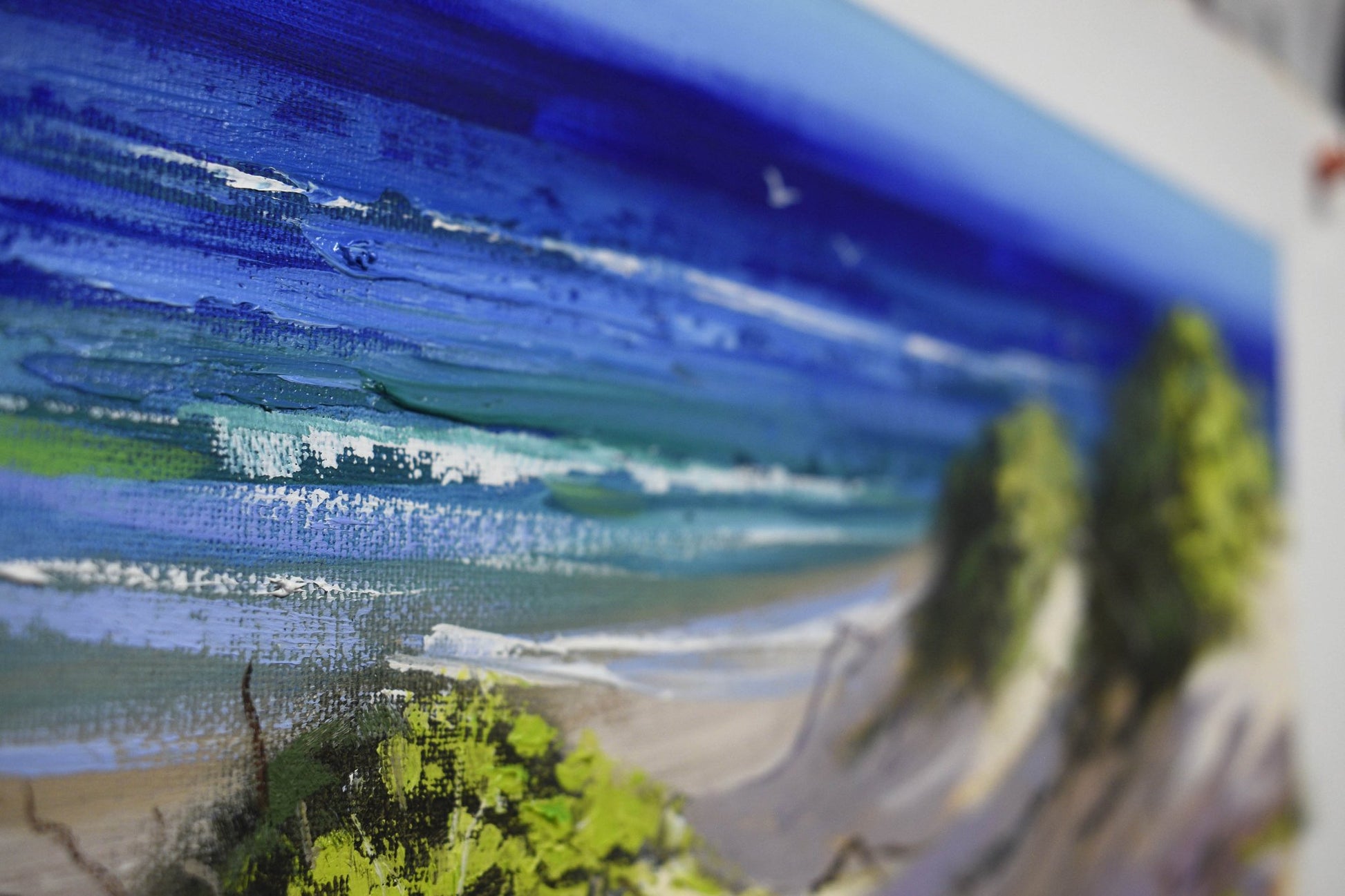Close-up of a beach scene with waves and cliffs, painted in a stylized manner.
