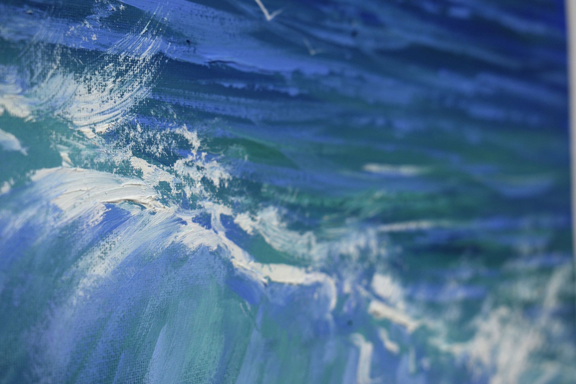 Close-up of a blue and green abstract painting with swirling patterns.