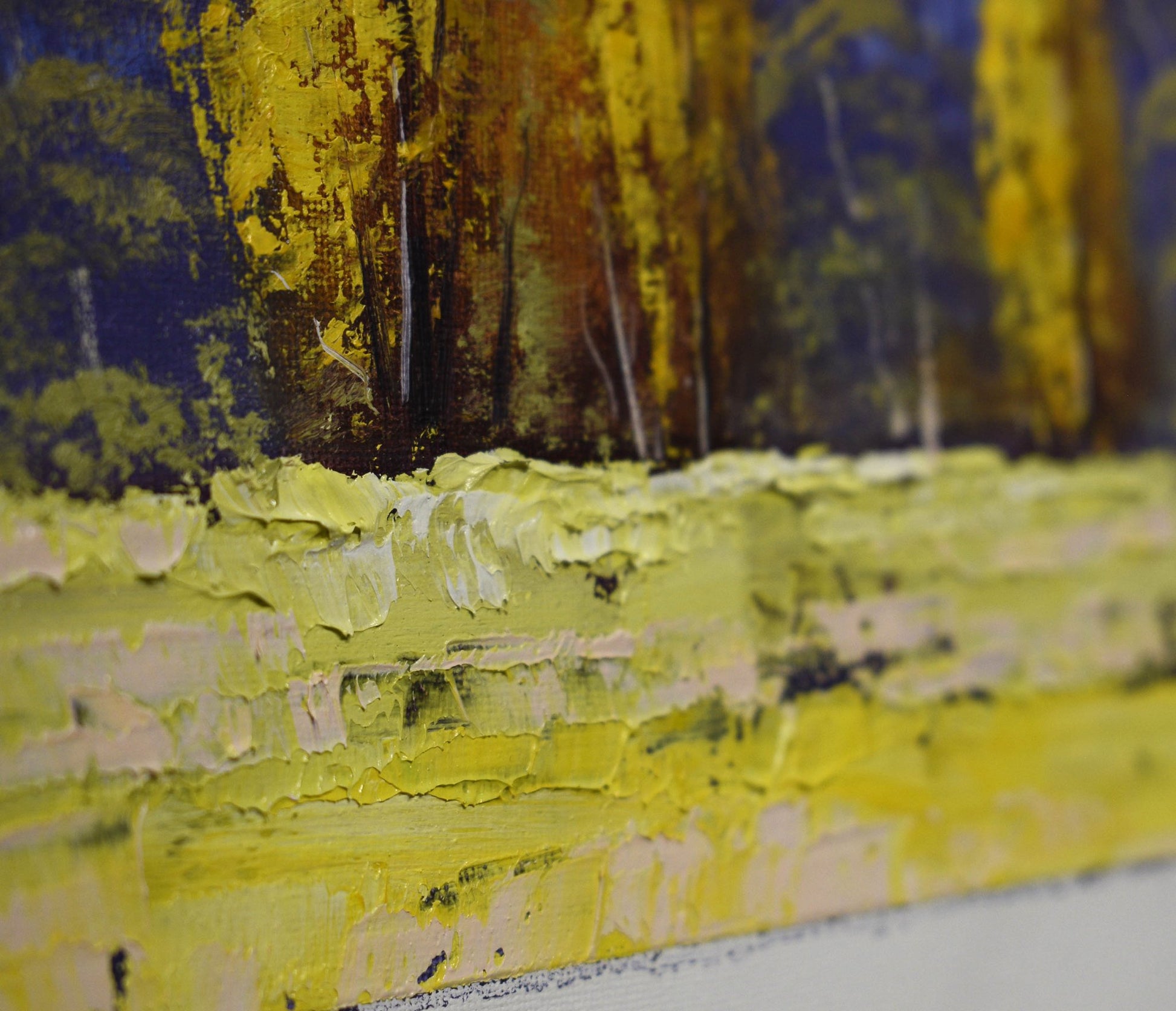 Close-up of a textured yellow and brown landscape painting with trees in the background.