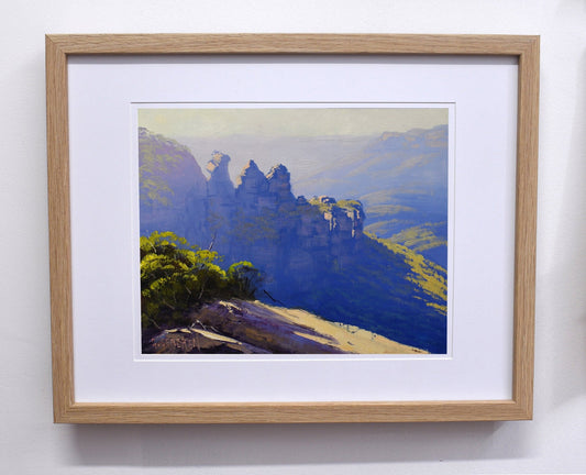 Framed painting of a mountain landscape with a wooden frame.