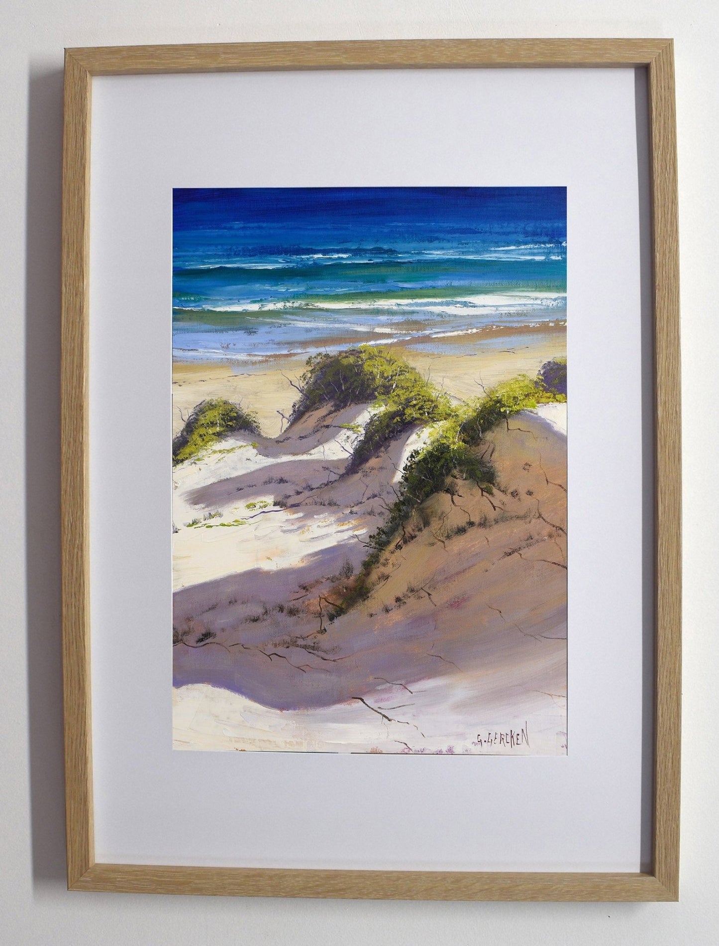 Framed artwork of a beach scene with sand dunes and ocean.