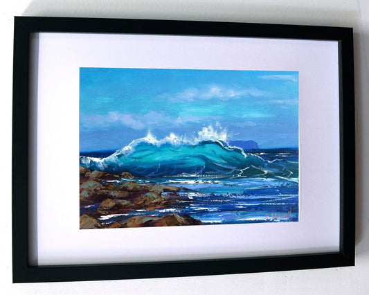 Framed artwork of a coastal scene with waves crashing against rocks.